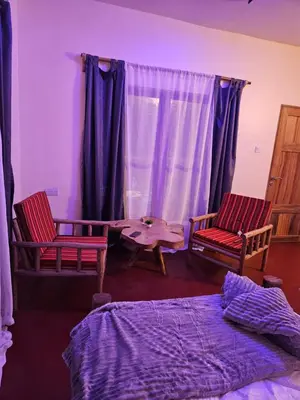 a bedroom with two chairs and a bed and a table at African Royal Villa and Campsite in Karatu