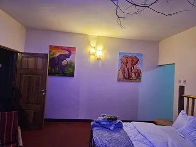 a bedroom with three paintings on the wall and a bed at African Royal Villa and Campsite in Karatu
