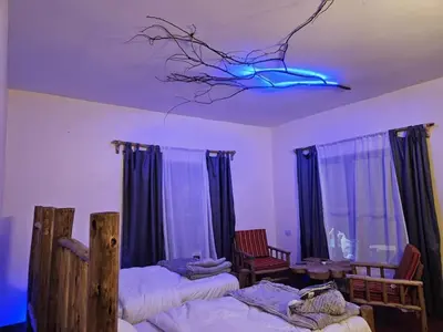 a room with three beds and a blue light on a ceiling at African Royal Villa and Campsite in Karatu