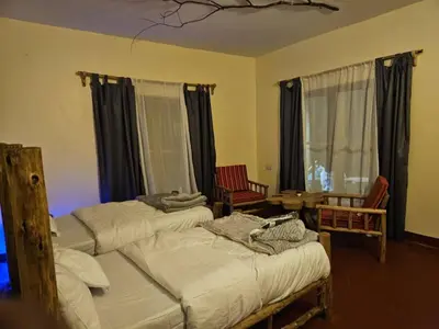 a bedroom with two beds and a table and chairs at African Royal Villa and Campsite in Karatu