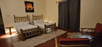 a living room with two beds and a rug at African Royal Villa and Campsite in Karatu