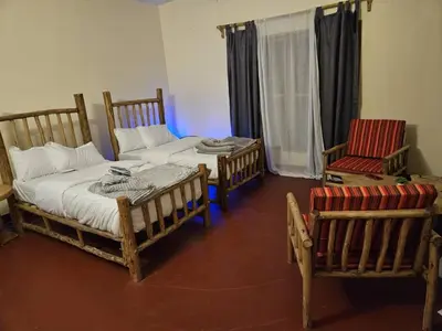 a room with two beds and two chairs in it at African Royal Villa and Campsite in Karatu