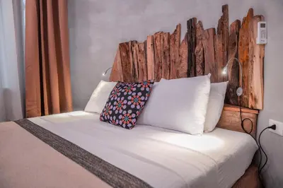 a bed with a wooden headboard and a pillow at Nyirenda Homestay Kilimanjaro in Moshi