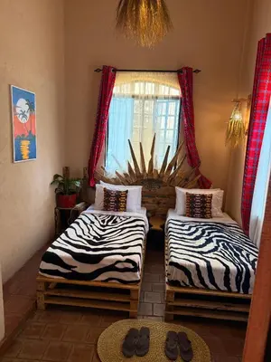 two twin beds in a room with a window at Serengeti Home in Arusha