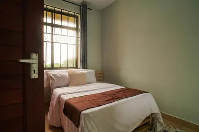a small bedroom with a bed and a window at Bluezone Residence in Arusha