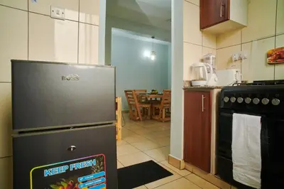 a kitchen with a refrigerator next to a table at Bluezone Residence in Arusha