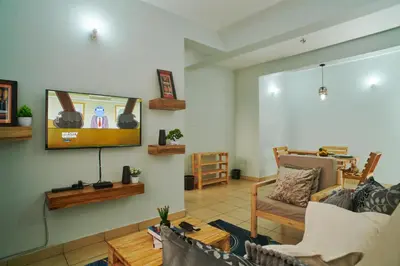 a living room with a flat screen tv on the wall at Bluezone Residence in Arusha