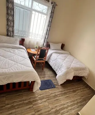two beds in a room with a table and a window at Boma villa kilimanjaro in Boma la Ngombe