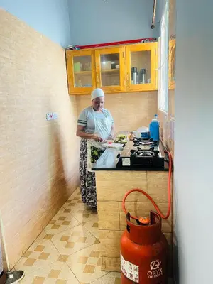 a woman standing in a kitchen preparing food at Boma villa kilimanjaro in Boma la Ngombe