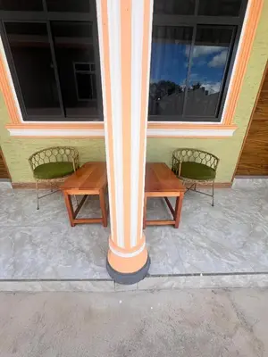 two benches sitting outside of a house with a column at Boma villa kilimanjaro in Boma la Ngombe