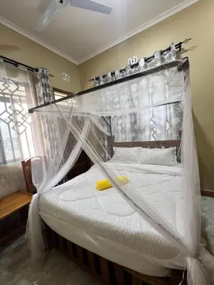 a bedroom with a bed covered in mosquito net at Boma villa kilimanjaro in Boma la Ngombe