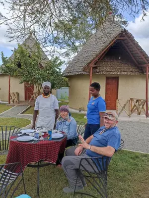 a group of people sitting at a table in front of a house at Oiti Boma Lodge Arusha in Arusha