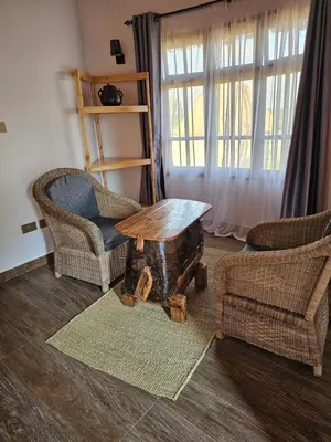 a living room with a table and chairs and a window at Oiti Boma Lodge Arusha in Arusha
