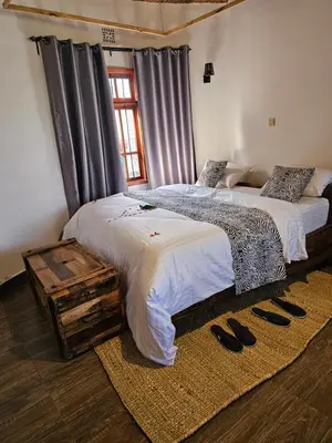 two beds in a room with shoes on the floor at Oiti Boma Lodge Arusha in Arusha
