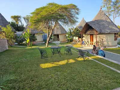 a dog laying on the grass next to a table and chairs at Oiti Boma Lodge Arusha in Arusha