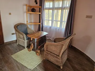 a living room with two chairs and a table at Oiti Boma Lodge Arusha in Arusha
