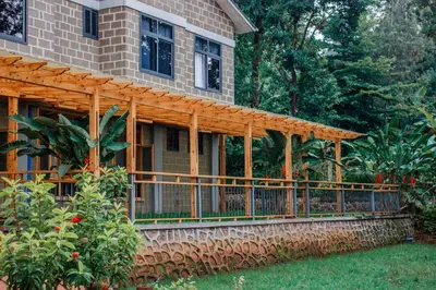 a wooden pergola on the side of a house at Avocado Kilimanjaro Homes in Marangu