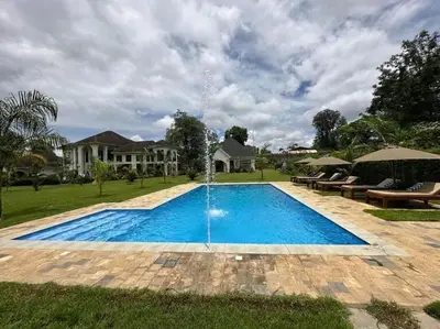 a swimming pool with a fountain in front of a house at Arusha Farm House in Arusha