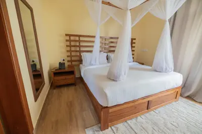 a bedroom with a canopy bed with white sheets at Arusha Farm House in Arusha