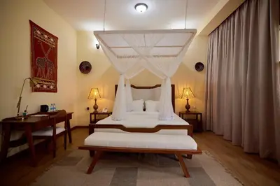 a bedroom with a bed and a table and a desk at Arusha Farm House in Arusha