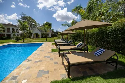 a row of lounge chairs with umbrellas next to a pool at Arusha Farm House in Arusha