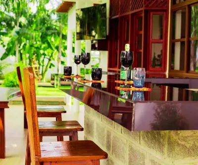 a bar with glasses of wine on top of it at Hellens Riverside Villa Luxury Garden Room in Msaranga