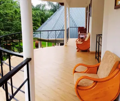 a living room with a wooden floor and chairs at Hellens Riverside Villa Luxury Garden Room in Msaranga