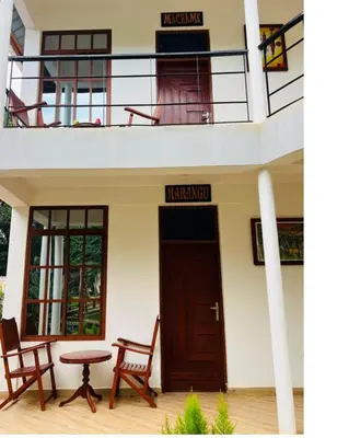 a building with a wooden door and a table and chairs at Hellens Riverside Villa Luxury Garden Room in Msaranga