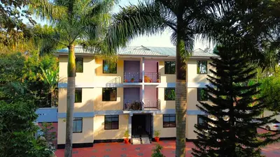 a building with palm trees in front of it at Kilimanjaro Helichrysum Homes in Arusha