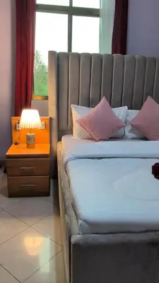 a bedroom with a bed and a lamp and a window at Kilimanjaro Helichrysum Homes in Arusha