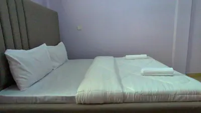 a bed with white sheets and pillows in a room at Kilimanjaro Helichrysum Homes in Arusha