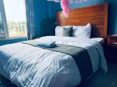 a blue bedroom with a large bed with a wooden headboard at Elly Villa Hotel in Moshi