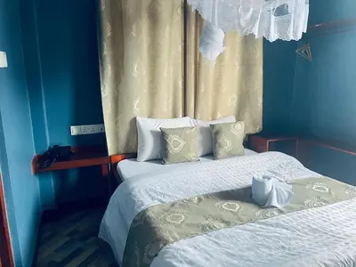 a blue room with two beds and a window at Elly Villa Hotel in Moshi