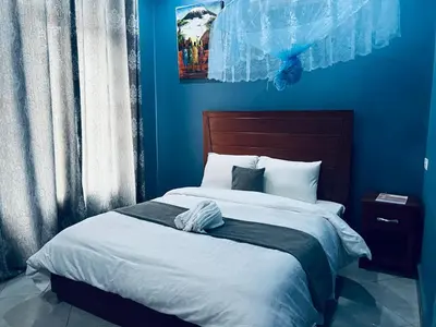 a blue bedroom with a large bed with blue walls at Elly Villa Hotel in Moshi