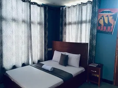 a bedroom with a bed with blue walls and curtains at Elly Villa Hotel in Moshi