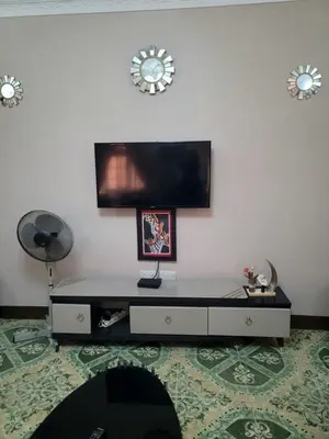 a living room with a table and a tv on a wall at Cape Haven in Arusha