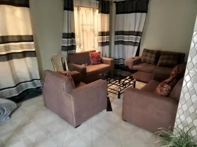 a living room with couches and chairs and curtains at World Heart Africa Experience in Arusha