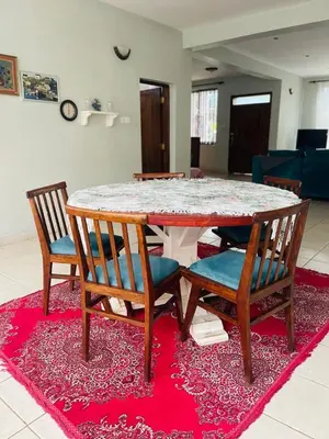 a dining room table with four chairs on a rug at LAVENDER Residence Arusha in Arusha