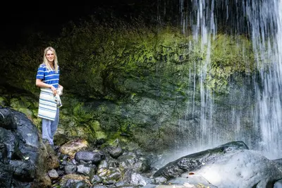 a woman standing in front of a waterfall at Koroi Forest Camp in Arusha