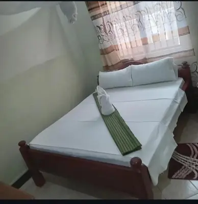 a white bed in a room with a window at Otakef Motel in Arusha