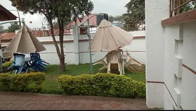 a patio with a table and an umbrella and chairs at Otakef Motel in Arusha