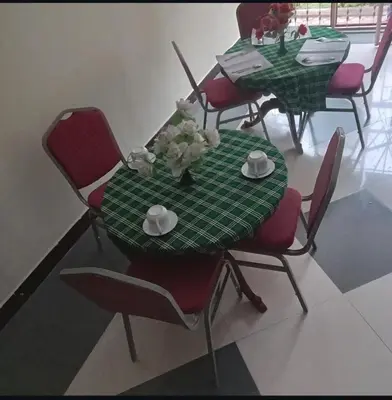 a table and chairs with a green table and flowers on it at Otakef Motel in Arusha