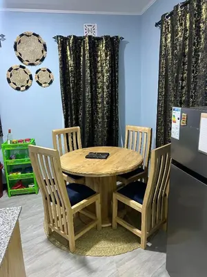 a wooden table with two chairs and a refrigerator at Upendo Moja House in Nkoanrua