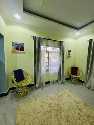 a living room with two chairs and a window at Upendo Moja House in Nkoanrua