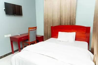 a bedroom with a bed with a red headboard and a desk at Lavish Homestay in Msaranga