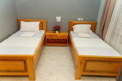 two twin beds in a room with flowers on the table at Lavish Homestay in Msaranga