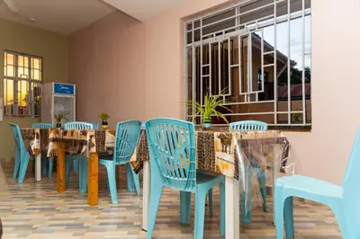 a dining room with blue chairs and tables at Lavish Homestay in Msaranga