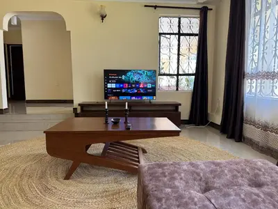 a living room with a coffee table and a tv at Maasai house in Arusha