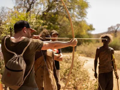 a man aiming a bow and arrow at a group of people at White House Hostels - Arusha in Arusha