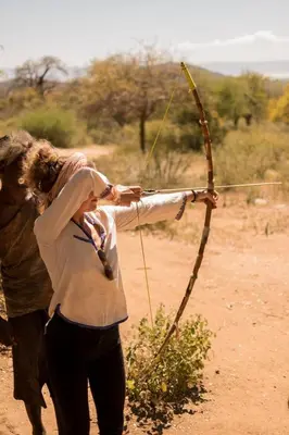 a woman holding a bow and arrow in a field at White House Hostels - Arusha in Arusha